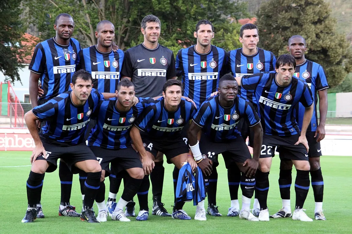 Inter Milan players posing for a team photo in black and blue striped shirts with Pirelli on the front