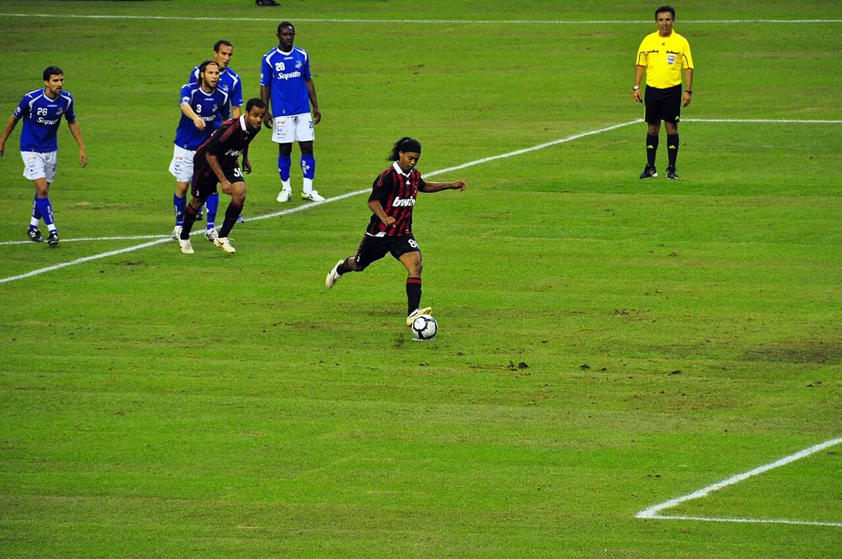 Ronaldinho in a red and black striped AC Milan shirt, number 80, about to take a penalty