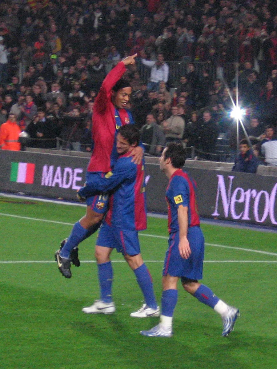 Ronaldinho in the red and blue Barcelona shirt, number 10, celebrating a goal with two team-mates